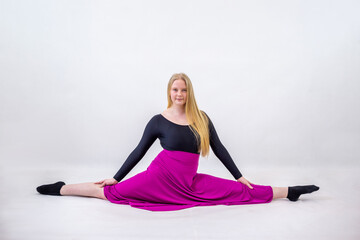 Young blonde blue-eyed dancer woman in long purple skirt on white background