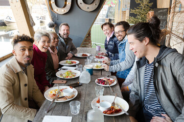 Portrait of smiling friends eating at restaurant outdoor patio