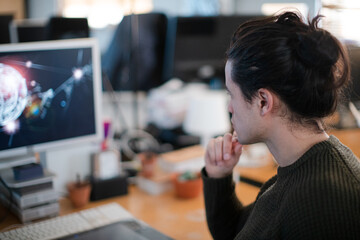 Smiling young man with long hair, working at computer