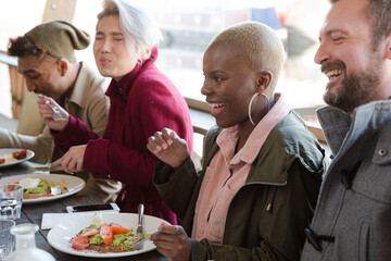 Portrait of smiling friends eating at restaurant outdoor patio