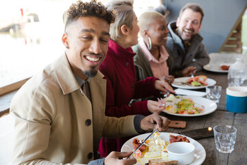 Smiling friends eating at restaurant outdoor patio