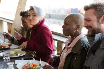 Portrait of smiling friends eating at restaurant outdoor patio