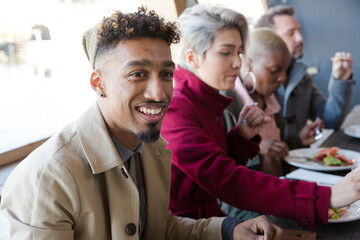 Obraz premium Smiling friends eating at restaurant outdoor patio