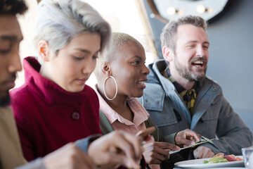 Smiling friends eating at restaurant outdoor patio