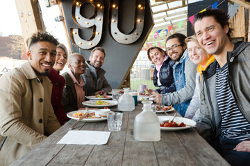 Portrait of smiling friends eating at restaurant outdoor patio