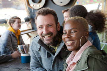 Portrait of smiling couple dining with friends at restaurant outdoor patio