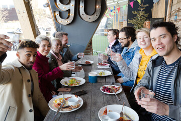 Portrait of smiling friends eating at restaurant outdoor patio