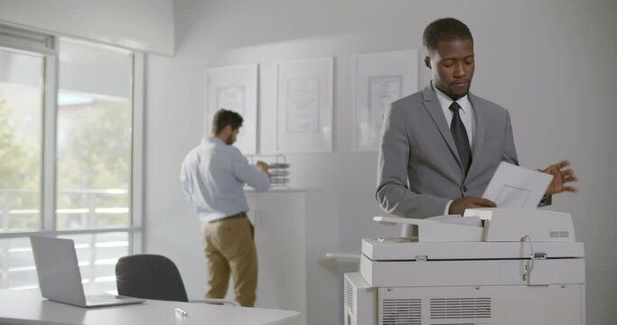 Afro-american businessman operating copy machine in modern office
