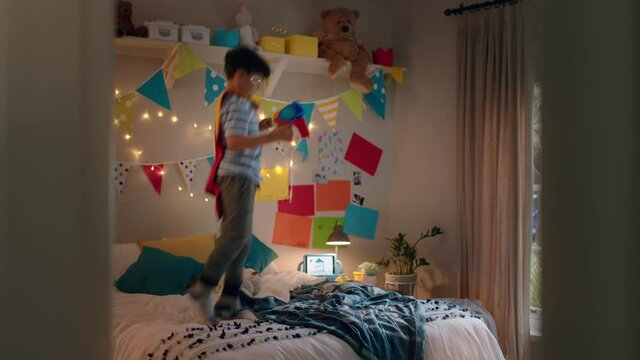 happy little boy jumping on bed wearing costume playing game enjoying playful imagination in colorful bedroom at home