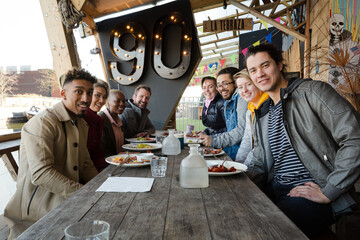 Portrait of smiling friends eating at restaurant outdoor patio