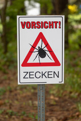 sign with german inscription of "Attention! Ticks", focus on foreground