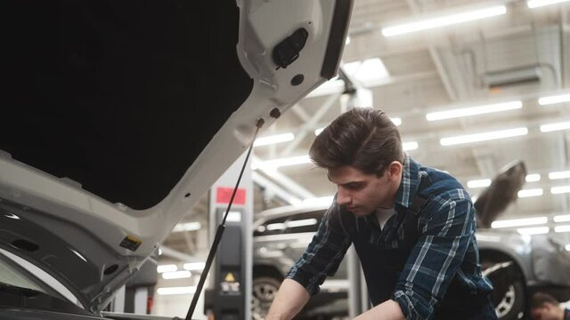 Focused confident auto mechanic man fixing car working in garage indoors