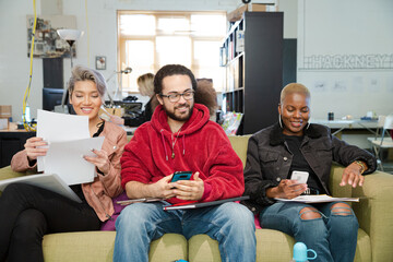 Smiling friends working together on sofa