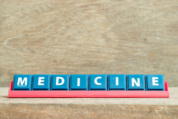 Tile alphabet letter with word medicine in red color rack on wood background