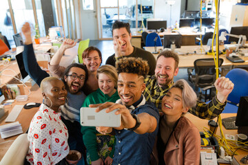 Team talking group selfie with smartphone in office