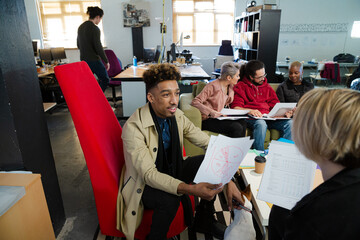 Colleagues discussing paperwork in office