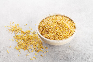 bulgur grits in a bowl on gray background, space for text, horizontally