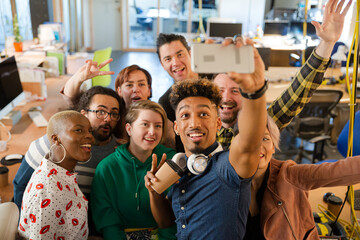 Team taking group selfie with smartphone in office