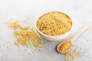bulgur grits in a bowl on a napkin, gray background, space for text, horizontally