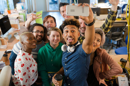 Team taking group selfie with smartphone in office
