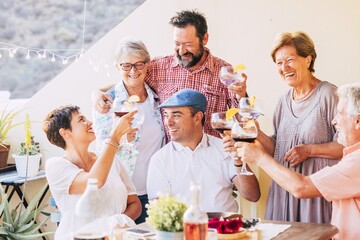Multi generation caucasian family toasting wine glasses and celebrating a get together at open terrace of house. Loving family drinking wine and enjoying leisure time together