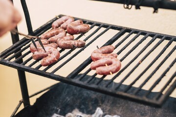 Hand cooking sausage meat on metal barbecue grill. Cooking fresh meat on bbq grill outdoor home or restaurant cooking
