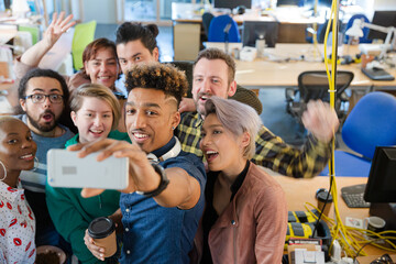 Team taking group selfie with smartphone in office