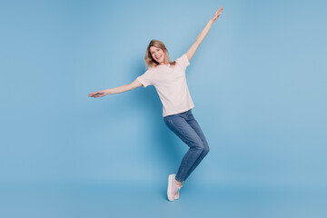 Fototapeta na wymiar Portrait of positive cheerful lady stand tiptoes raise hands enjoy discotheque on blue background