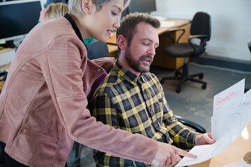 Man and woman discussing paperwork at desk