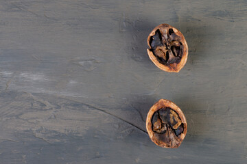 half of a split rotten walnut on a brown concrete or slate background. The concept of a walnut background. top view. A natural product. damaged product