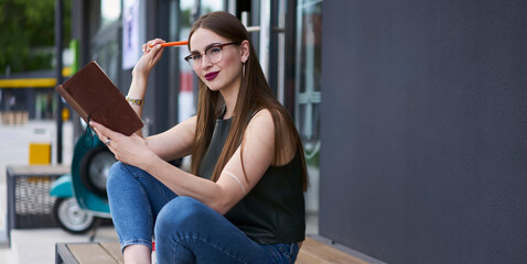 Contemplative hipster girl in optical spectacles for provide eyes correction thoughtful looking away while thinking about homework task, Caucasian female student with education textbook learning