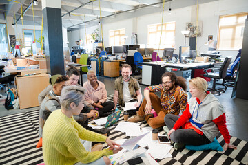 Team sitting on floor, discussing paperwork