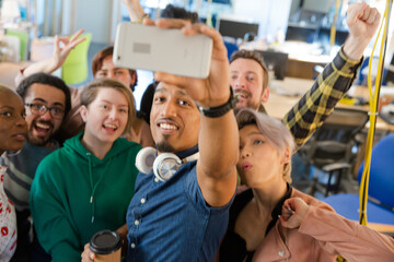 Team taking group selfie with smartphone in office