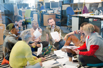 Team sitting on floor, discussing paperwork