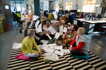 Team sitting on floor, discussing paperwork