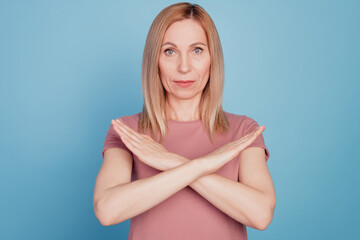 Portrait of serious unhappy confident woman crossed hands gesturing no refuse sign isolated on blue...