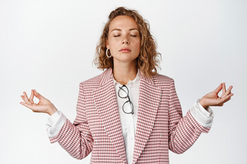 Young patient business woman, corporate manager close eyes and meditating, relaxing with yoga,...