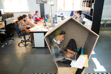 Young man working at laptop in modern armchair