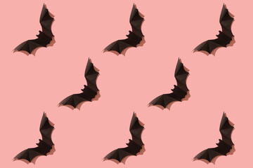 Black paper bat on a pink background. Halloween concept. With a hard black shadow. View from above.