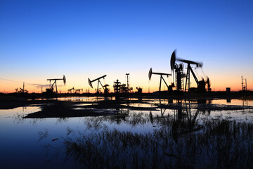Fototapeta na wymiar In the evening, oil pumps are running, Silhouette of beam pumping unit