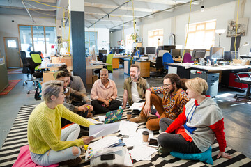 Team sitting on floor, discussing paperwork