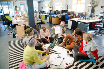 Team sitting on floor, discussing paperwork