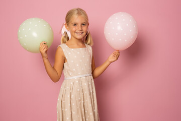 Adorable little kid with balloons and cake isolated over pink background. Celebration concept.