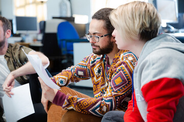 Team sitting on office floor, discussing paperwork