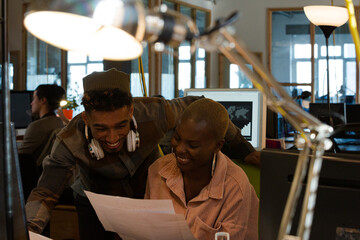Man and woman discussing paperwork at computer