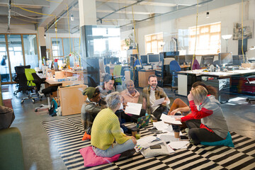Team sitting on floor, discussing paperwork