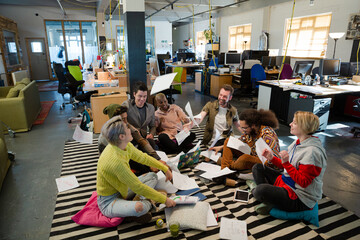 Team sitting on floor, discussing paperwork