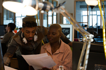 Man and woman discussing paperwork at computer
