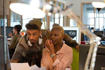 Man and woman discussing paperwork at computer