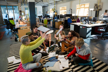 Team sitting on floor, discussing paperwork